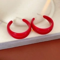 Close-up of red C-shaped resin hoop earrings with glossy finish on a beige display stand - Red