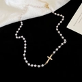 Dettaglio della collana di perle bianche con ciondolo a croce dorata lucida e chiusura a moschettone - Oro