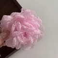 Gros plan d'une pince à cheveux rose en forme de rose tenue à la main sur une boîte en bois - Pince à cheveux / Rose
