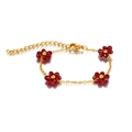 Detail of bohemian gold chain bracelet featuring red beaded flowers and lobster clasp - Dark Red