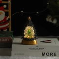 Détail d'une boule à neige sapin de Noël lumineux avec socle doré et paillettes - Sapin de Noël vert