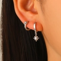 Dettaglio ravvicinato di orecchini a stella asimmetrici in argento su una modella - Orecchini Huggie con Ciondolo a Stella (4493) / Bianco K / Argento