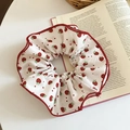 Dettaglio scrunchie in raso con stampa a fragola e bordi smerlati rossi su libro - Bianco-Rosso (Stampa a Fragola)