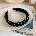 Detail of black pleated fabric headband with white pearls on a decorative tray - Black