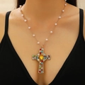 Golden cross necklace with colorful rhinestones and white pearls shown on neck - Gold Colored Gemstone Cross Pearl Chain (DZ-211)