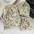 Flat lay of floral drawstring storage bags in three sizes on a white desk workspace - Tiny Floral Green