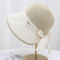 Elegant two-tone straw sun hat with bow tie and metal LUCKY badge on display stand - Beige