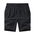Détail du short de course avec poches zippées, accents orange et ceinture élastique ajustable - M / Noir