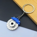 Macro shot of silver metal brake disc keychain with blue caliper on wood background - Brake Disc / Blue