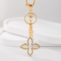 Goldener Kleeblatt-Schlüsselanhänger mit Diamanten auf geometrischem Ständer - Gold