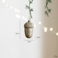 Sparkling gold acorn Christmas tree ornament hanging on pine needles with bokeh lighting - Champagne Resin Acorn
