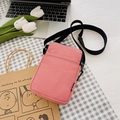 Pink corduroy crossbody bag with adjustable black strap shown in a lifestyle flat lay - Rose Red