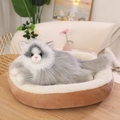 Realistic grey and white ragdoll cat plush toy resting on a round brown pet bed - Gray / 50cm