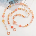 Detail of warm orange beaded phone strap with matte flower and butterfly charms - Orange Mixed Color Beads