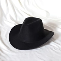 Detail view of the classic black wool felt cowboy hat with a curved brim on fabric - Black