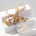 Gouden oceaan sleutelhanger met schelp, zeester en glitterbal op witte achtergrond - Meerkleurig