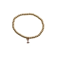 Macro detail of gold beaded bracelet with a colorful zircon-inlaid letter I pendant - Letter I