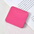Pink square portable cosmetic mirror shown on an open book page in a minimalist setting - Rose Red