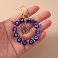 Goldener Hamsa-Hand-Schlüsselanhänger mit blauen Nazar-Augen-Perlen für Taschen - Blaue Augenpalme