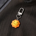 Cute sunflower resin keychain with a smiling face and orange petals on textured fabric - Sun (F523K)