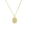 Close-up of golden rectangular zircon pendant with letter B on a delicate cross chain - Necklace B
