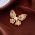 Elegante spilla a farfalla in oro con perla champagne e zircone su sfondo di seta - Spilla N. 1 - Oro - Placcato Oro Vero