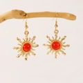 Close-up of golden sun-shaped earrings with red gemstones hanging on a branch - Sun Drop Earrings Red Rhinestone (7239) / Gold Red