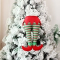 Gambe di elfo di Natale a righe rosse e verdi appese su un albero innevato - Stile Elfo Rosso