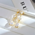 Macro detail of elegant gold drop earrings featuring teardrop and oval shaped zircons - White
