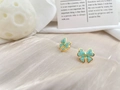 Detail of gold-plated bow earrings with blue enamel finish on pearlescent fabric - Teal Blue