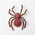 Detailed view of spider brooch with vibrant red crystals and golden alloy setting - Dark Red