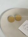 Makro-Detail goldener Hohlkugel-Ohrringe mit Perlenstruktur auf Keramikteller - Hohlkugel-Ohrstecker / Gold