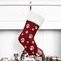 Red velvet Christmas stocking with white paw prints and embroidered snowflakes on fireplace - Red
