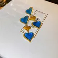 Dettaglio di orecchini vintage a cuore in oro e blu su una scatola di pelle bianca - Orecchini a cuore tricolore a strati oro e blu (Silver Earring Post)