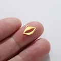 Creatieve 18K vergulde roestvrijstalen lippenhanger getoond op een vingertop - Goud