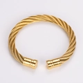 Detail of gold twisted wire cable bracelet showing intricate weave and cylindrical ends - Gold