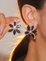 Elegant black flower stud earrings with shimmering crystal border on model's ear - Black Marquis Flower Style