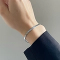 Close-up of minimalist silver flat snake chain bracelet on a wrist with black sleeve - Steel Color Snake Chain Bracelet