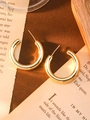 Macro detail of chunky gold C-shaped hoop earrings on vintage book page background - Gold Large C-Shape