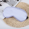 Lavender faux silk sleep mask with black elastic strap on woven mat, soft satin texture - Taro