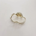 Close-up of irregular wave hair claw clip in creamy white enamel and gold metal finish - Cream
