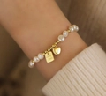 Natural freshwater pearl bracelet with golden heart and Good Luck charms on a woman's wrist - Good Luck Tag Freshwater Pearl Bracelet