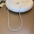 Detailed view of small white pearl necklace with gold clasp on white ceramic tray - Faux Pearl Necklace