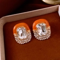 Close-up of orange enamel and crystal oval stud earrings on vintage velvet background - Silver Earring Post - Coffee