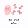 Macro shot of 9x7mm gold bow nail charm with pink rhinestones for festive manicure - A686