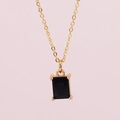 Gold chain necklace with black rectangular gemstone pendant on pink background - Black