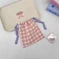 Detail of pink plaid drawstring organizer bag on a tray with lifestyle accessories - Pink Plaid Light Purple Cord