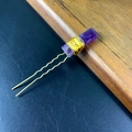 Macro detail of natural purple crystal stone wrapped in gold wire on a U-shaped hair pin - Amethyst