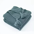 Sage green knitted waffle throw blanket with handmade decorative tassels on pure background - Malachite green