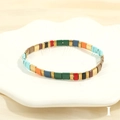 Macro detail of Bohemian Tila bead bracelet with colorful enamel blocks on a white tray - Multicolor I-Red Green Blue Orange Black Coffee Gold